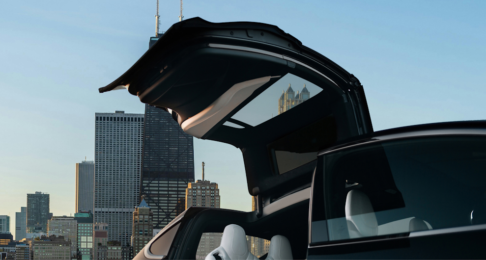 Luxury electric vehicle with open gullwing doors set against the Chicago skyline on a bright sunny day