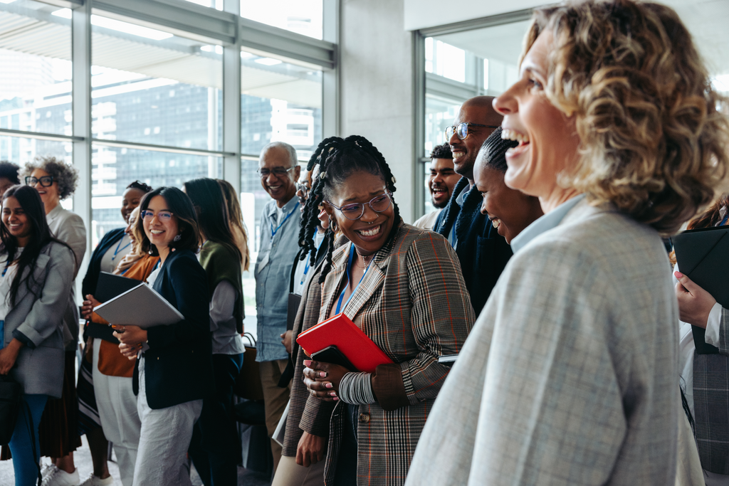 Diverse professionals smiling and networking at a corporate event.