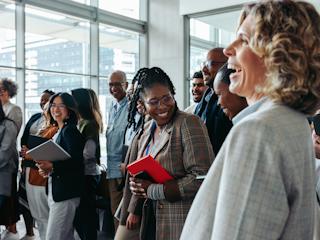 Diverse professionals smiling and networking at a corporate event.