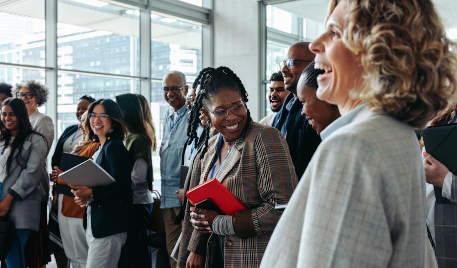 Diverse professionals smiling and networking at a corporate event.
