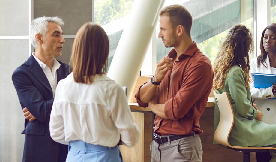 A group of professionals are having conversations in a modern office.