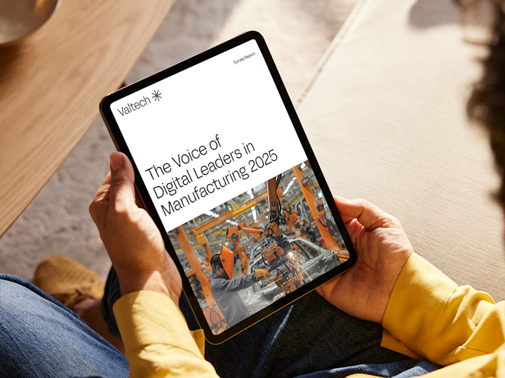 Person viewing Valtech survey report, The Voice of Digital Leaders in Manufacturing 2025, on tablet.