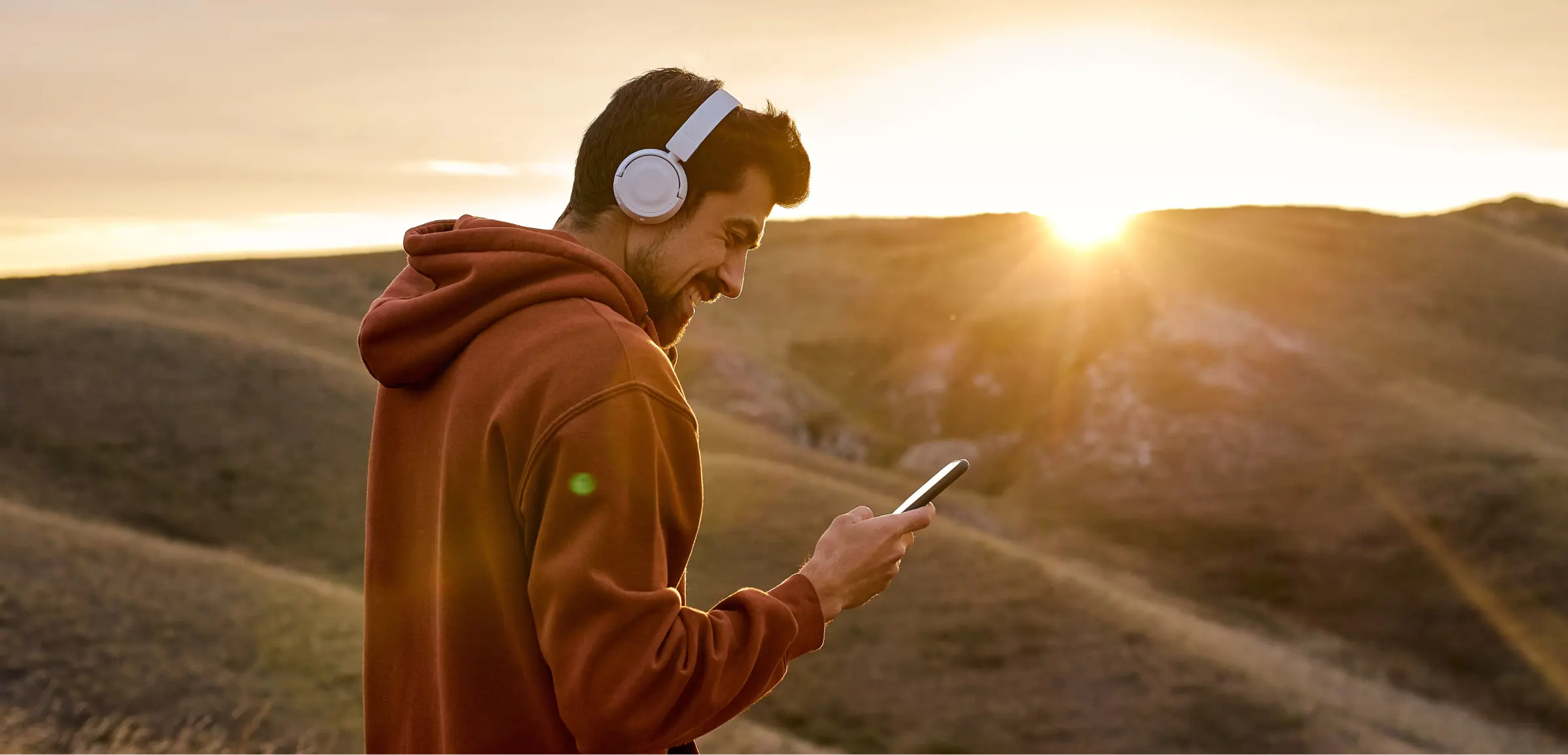 Transformative partnership man at sunset with headphones and smartphone Valtech